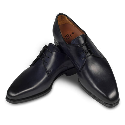 Anzugschuhe von Flecs, Plain Derby Schnürer in dunkelblau, durchgenäht. Paarweise Ansicht Schuhe überkreuzt aufgestellt. Bei Sisento.